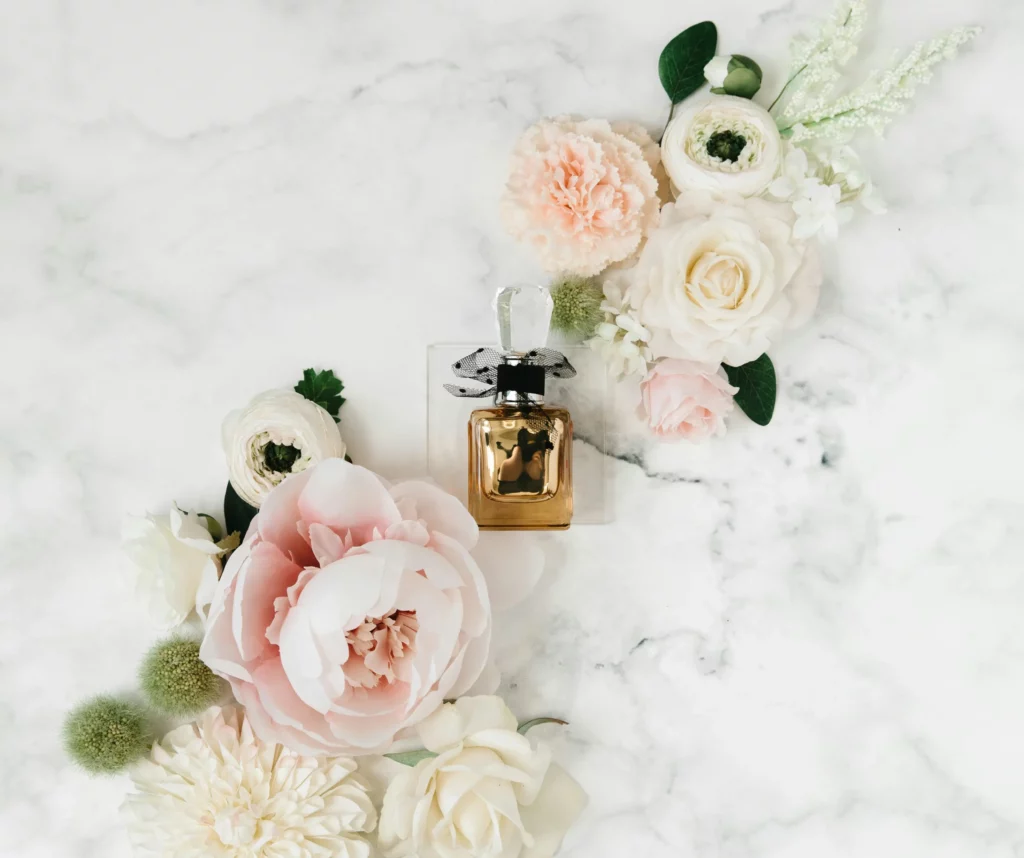 בקבוק בושם ומסביבו מונחים פרחים - בשמים ברמת גן